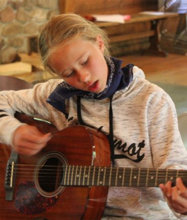 girl learning to play guitar